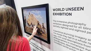 A lady in a red top feeling the tactile nature of an elevated photographic print of a rhino